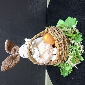 Fuzzy bunny In Basket of Golden Eggs Nestled In White floral Ring Of Flowers.